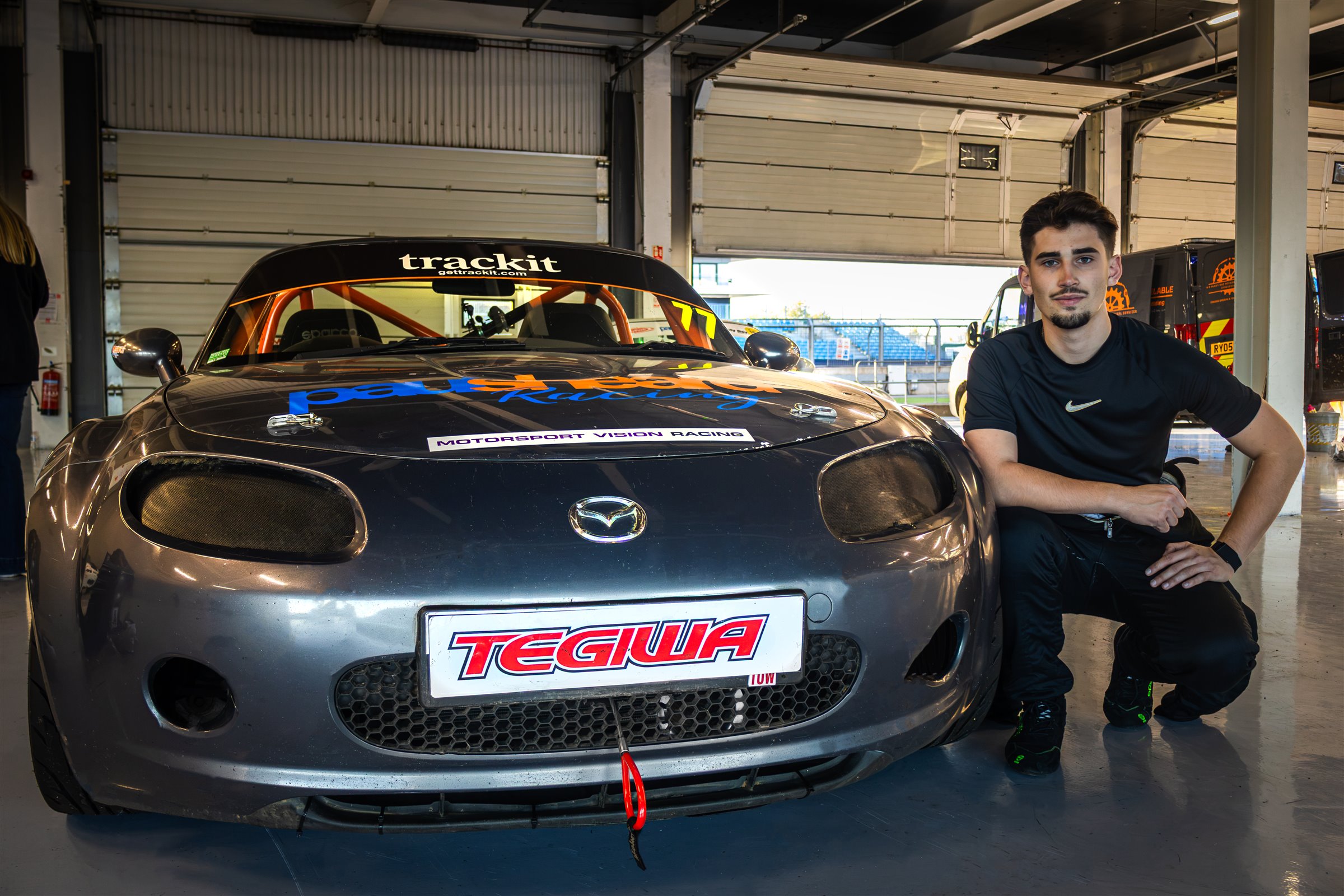 Christian Valverde crouching beside the front of the MX-5