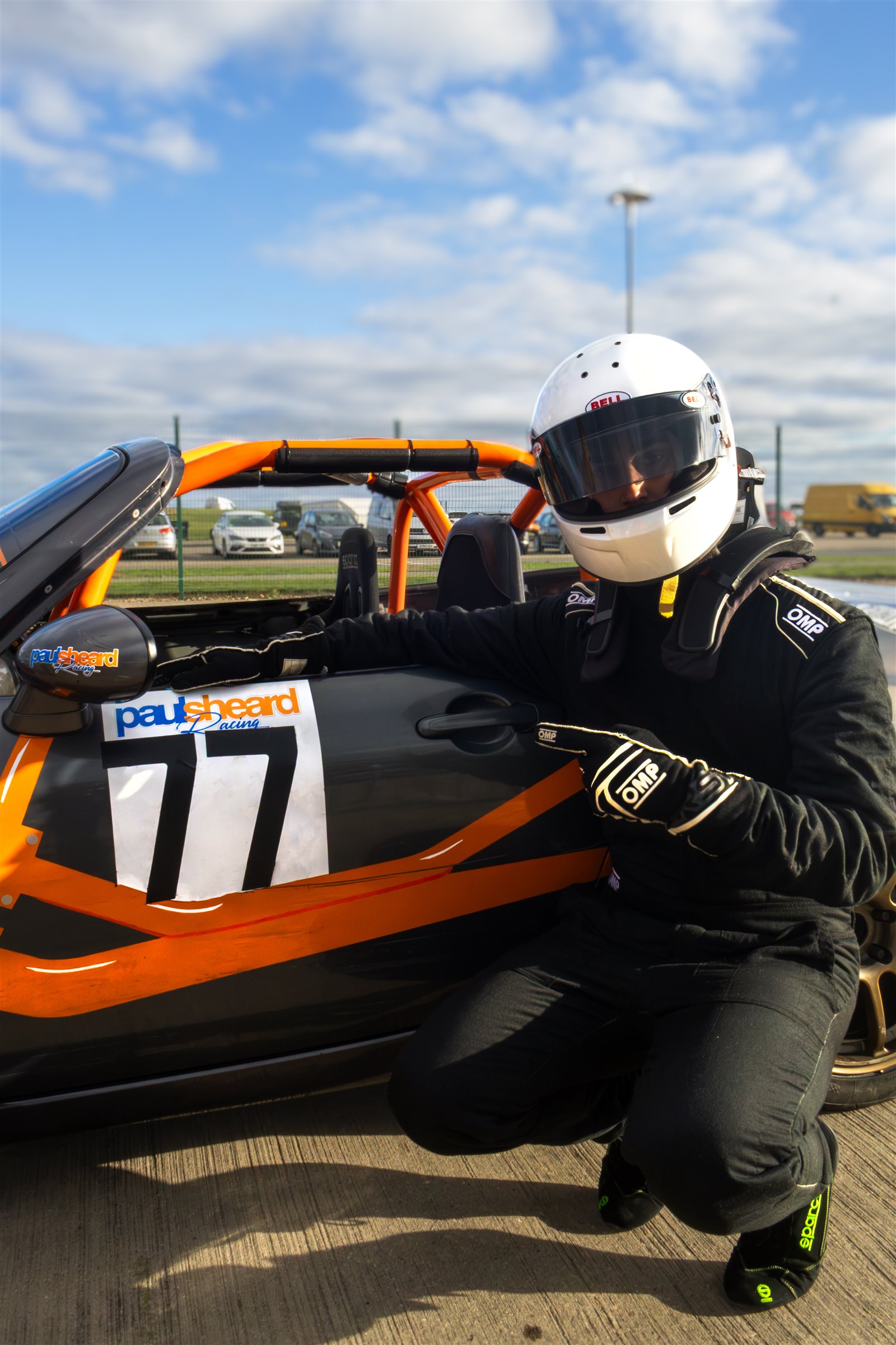 Christian Valverde crouching beside the number 77 MX-5